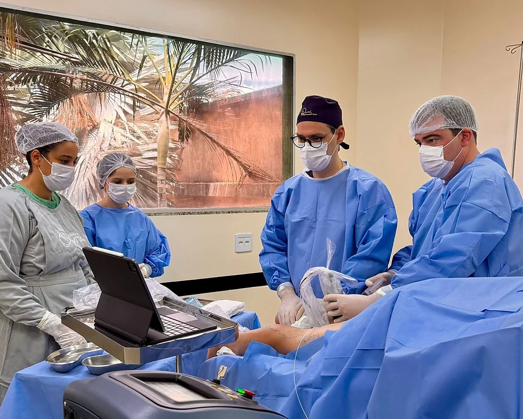 Equipe de avental azul e máscara no centro cirúrgico, com o aparelho de ultrassom em primeiro plano